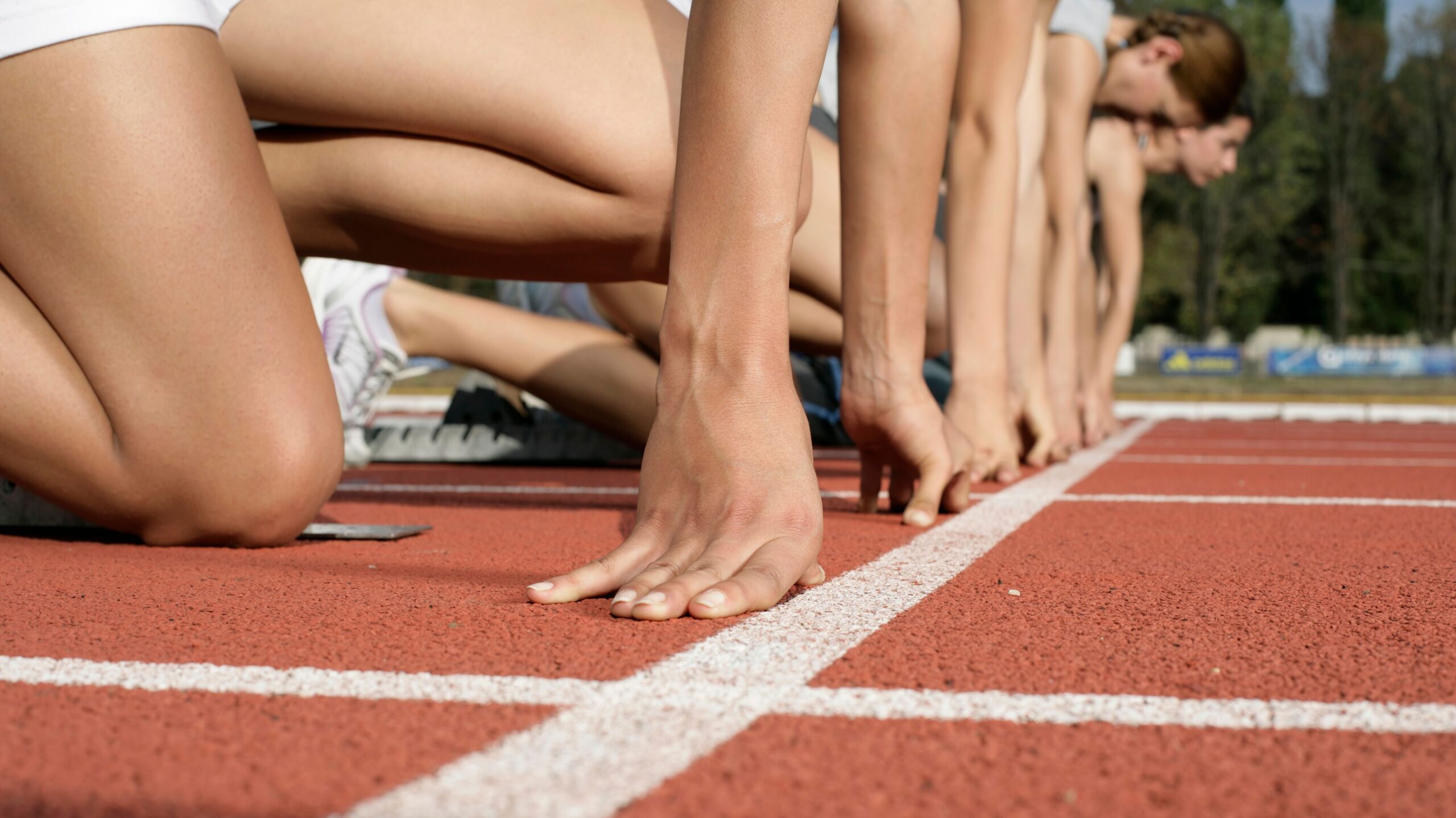 Close-up of runners at the starting line ready to race on a track field.
